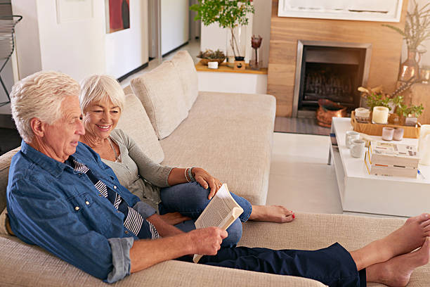 Couples who read together stay together Shot of a relaxed senior couple reading a book together on the sofa at home real wife stories stock pictures, royalty-free photos & images