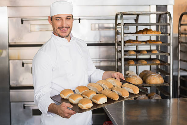istock Happy baker showing tray of fresh bread 538236721