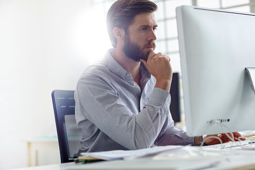 Shot of a handsome designer sitting at his desk with his computer in front of him