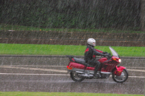 Brunssum, the Netherlands -July 13, 2014 : Passing motorcycle during a heavy rain shower. This day in July is very wet but in spite of this it gives him no trouble to com forward.