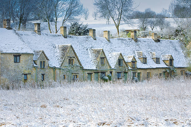Snow-covered terraced houses behind a wire fence, under a partly cloudy sky.  A metal exercise structure is visible in the yard in Harrogate, UK.