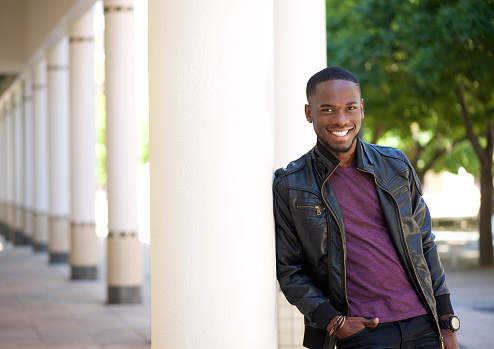 Close up portrait of an african american young man smiling in black leather jacket