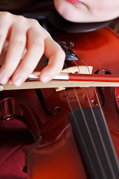 istock girl playing violin - bow in arm and strings 538264657