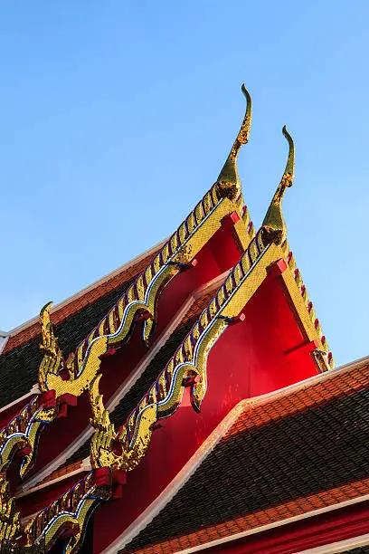 Golden stainglass ornament on wat thai roof in sunshine