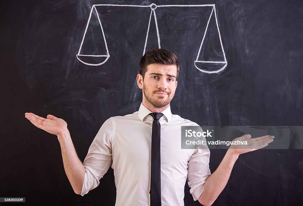 Social network Thinking about right solution. Young man is standing against blackboard with drawing weight.Thinking about different ways. Confident man is standing under three arrows directed in different directions, chalk drawing on blackboard. Choice Stock Photo