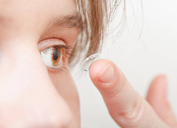 istock young woman inserts corrective lens in eye 538304059