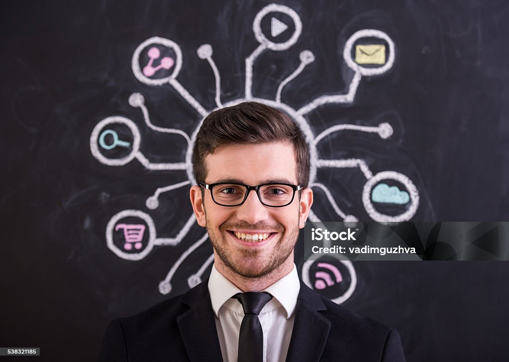 Social network Social network. Smiling young man is standing against social network chalk drawing on blackboard.Thinking about different ways. Confident man is standing under three arrows directed in different directions, chalk drawing on blackboard. 2015 Stock Photo