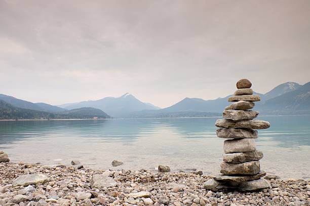 istock Balanced stone pyramide on shore, blue water of mountain lake. 538322330