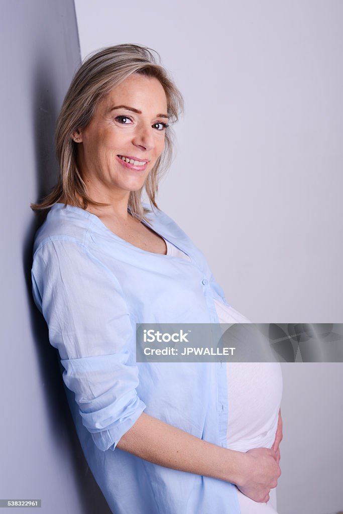 beautiful blonde mature pregnant woman blue shirt isolated gray background beautiful forty years old pregnant woman with blue shirt isolated on a gray background 2015 Stock Photo