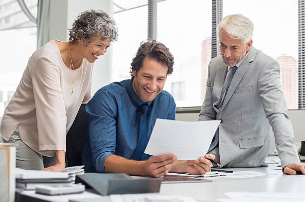 Business teamwork in meeting Business people working as a team at the office. Business partners discussing documents and ideas during meeting. Team of businesmen and senior businesswoman feeling happy after seeing final contract. cfo stock pictures, royalty-free photos & images
