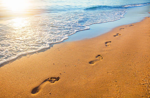 playa, onda y huellas en la puesta de tiempo - footprint sand sea beach fotografías e imágenes de stock