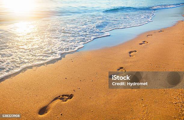 Beach Wave And Footprints At Sunset Time Stock Photo - Download Image Now - Footprint, Sand, Beach
