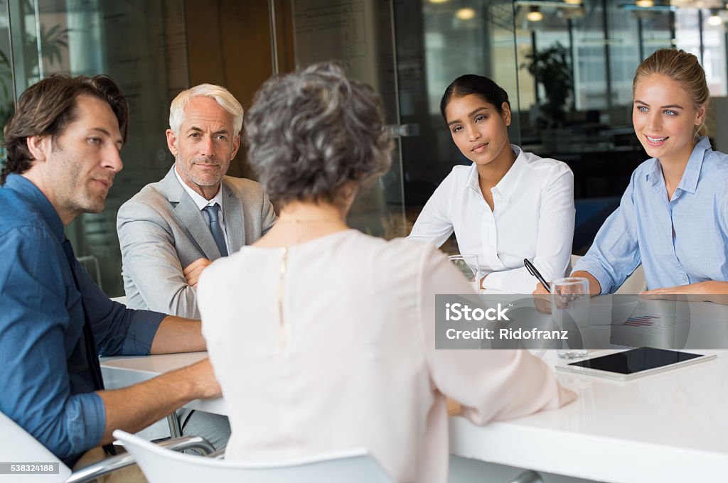 Business team in conversation Portrait of busy partners working together in office. Group of businessmen and businesswomen sitting in a board room while leadership talking to them. Business partners discussing documents. Senior Adult Stock Photo