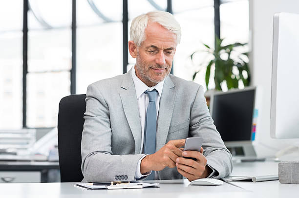 supérieur homme d'affaires sms avec poche pour téléphone portable - smirking senior men senior adult businessman photos et images de collection