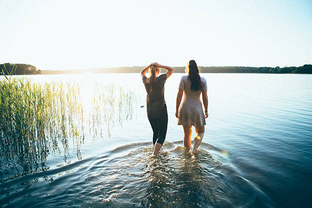istock rear view, two young woman walking into sunset over lake 538324936