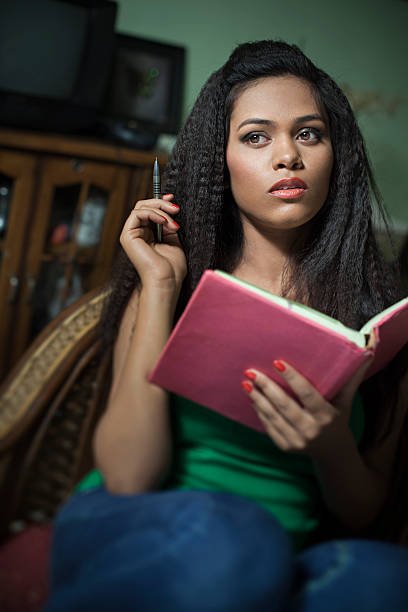 istock Girl student holding book and pen while studying at home. 538327320