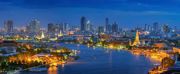 Panorama Views of Bangkok and the Chao Phraya River Wat Arun curve. Against a backdrop of high-rise buildings at dusk.