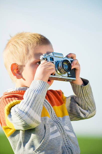 istock Little boy with an old camera shooting outdoor. 538331658