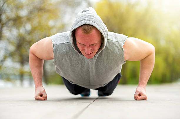 Active man doing push up in park. stock photo