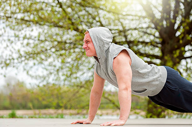 Active man doing push up in park. stock photo