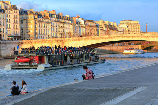 Paris, France - April 27, 2016: People sitting beside the river Seine, Paris France
