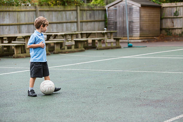 Lonely School Yard Soccer Boy in school uniform playing soccer alone in the school yard recess soccer stock pictures, royalty-free photos & images