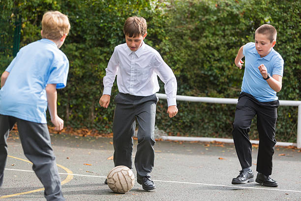 School Yard Soccer Competition Boy in school uniform playing soccer in the school yard recess soccer stock pictures, royalty-free photos & images