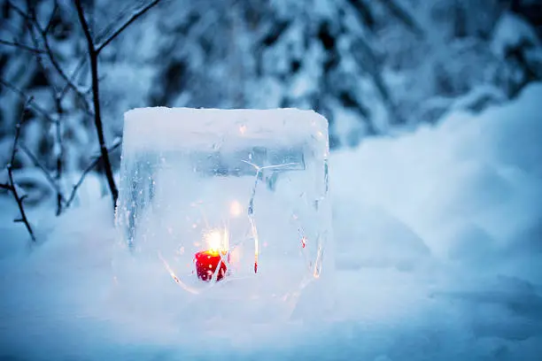 Ice lantern with red candle burning inside