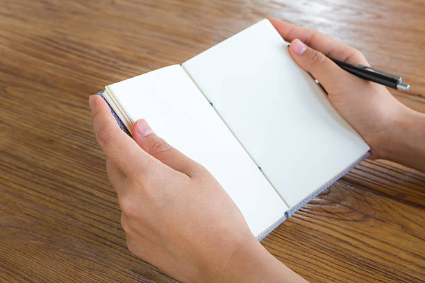 istock Hands with pencil and book on wood table 538340259