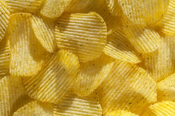 Photo of Backdrop of delicious potato chips with onion. Closeup