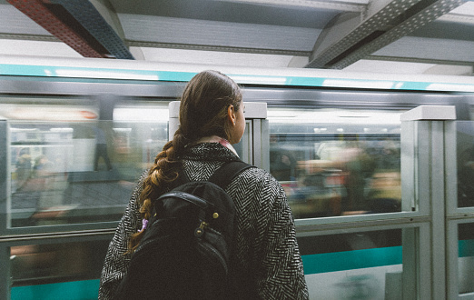 Young french girl waiting metro train at subway in Paris, France