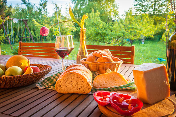 Wooden garden table with bread, cheese and wine Cottage Still Life spread food stock pictures, royalty-free photos & images