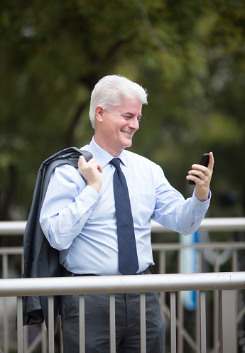 Cheerful businessman using his smart phone outdoors