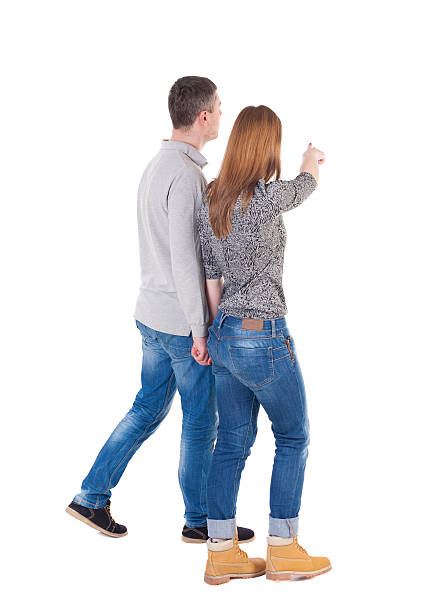 Back view of walking young couple Back view of walking young couple (man and woman) pointing. Rear view people collection. backside view of person. Isolated over white background/ pressed shoulders man and woman go and point out the finger on the target path pics of girls buttocks stock pictures, royalty-free photos & images