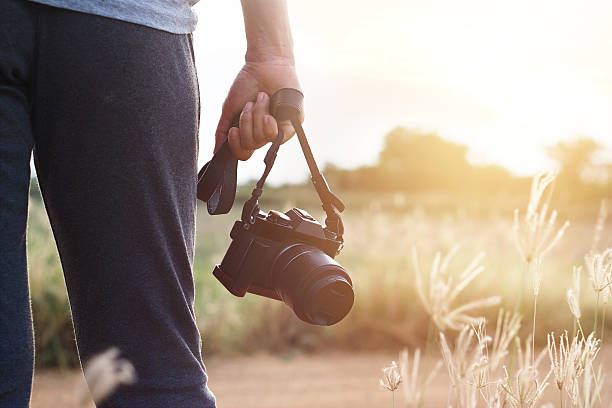 istock woman holding camera in hand on sunset nature background 538354662