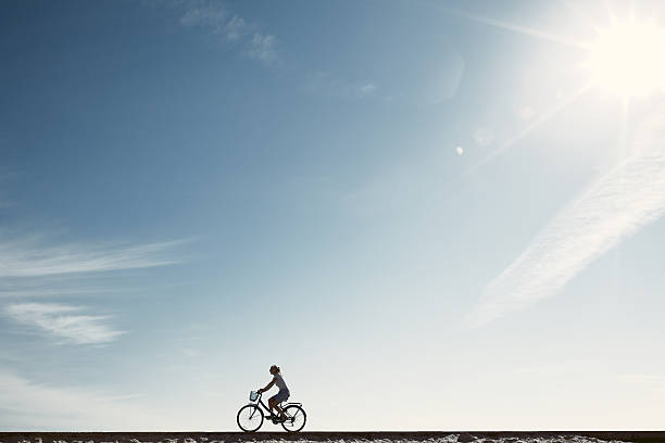 Silhueta de menina a desfrutar de bicicleta - fotografia de stock