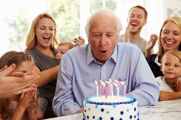 nonno soffia le candeline sulla torta di compleanno festa di famiglia - soffiare foto e immagini stock