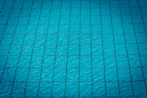 Water surface and blue tiles pattern at the bottom of swimming pool. Useful for summer and swimming background. Space for copy.    