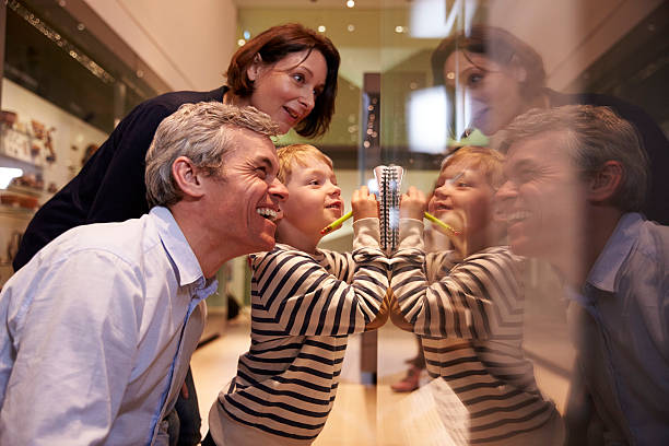 Family Looking At Artifacts In Glass Case On Trip Family Looking At Artifacts In Glass Case On Trip To Museum museum stock pictures, royalty-free photos & images