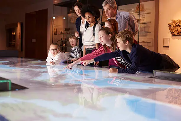 Photo of Pupils On School Field Trip To Museum Looking At Map