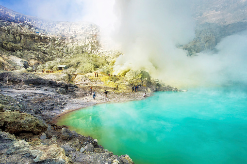 Ijen Volcano, East Java, Indonesia - May 25, 2013: Sulfur mining operation next to the world's largest acidic lake inside the crater of Kawah Ijen volcano in East Java, Indonesia.