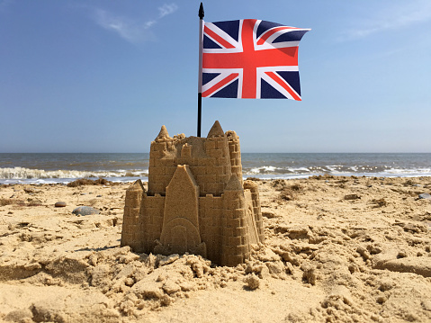 A sandcastle on an English beach with a UK flag