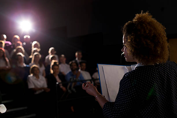 Making a Speech Female teacher giving a speech in a lecture hall to students and teachers. woman press conference stock pictures, royalty-free photos & images