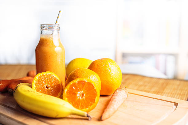 Smoothie in a glass bottle made from fresh oranges, lemon bananas and carrots