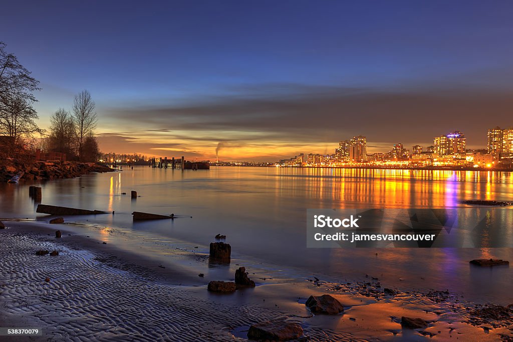 Sunset glow with city lights on New Year's Day Sunset glow and city lights reflecting over river water and beach, Surrey, British Columbia, Canada Christmas Tree Stock Photo