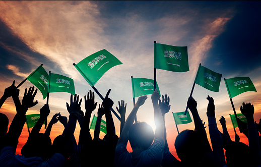 Siluetas de personas sosteniendo bandera de Arabia saudí photo