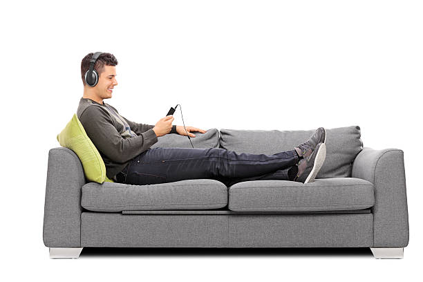 istock Young guy lying on sofa and listening to music 538392033