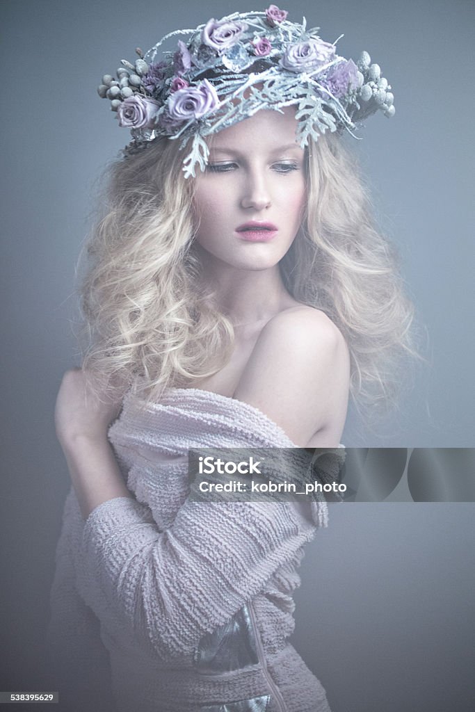 Girl with flowers on her head in a dress  Girl with flowers on her head in a dress in the Russian style. Picture taken in the studio. Fog effect. 2015 Stock Photo