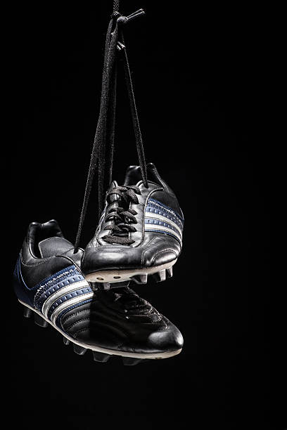 Soccer shoes hanging on black background Pair of soccer shoes hanging on black background football boot stock pictures, royalty-free photos & images