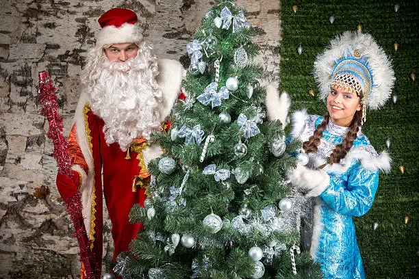 Russian Santa Claus and Snow-maiden peeking from behind the Christmas tree